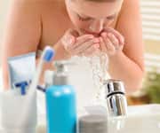 Woman washing face above bathroom sink