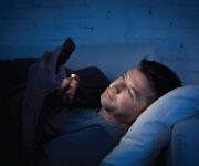 Sleep and Circadian Rhythm - man on cellphone while lying in bed