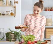 woman pouring dressing on salad