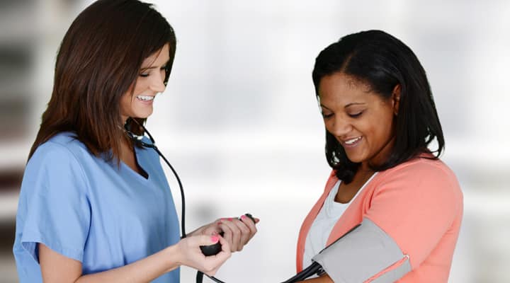 Woman with having her blood pressure taken by nurse