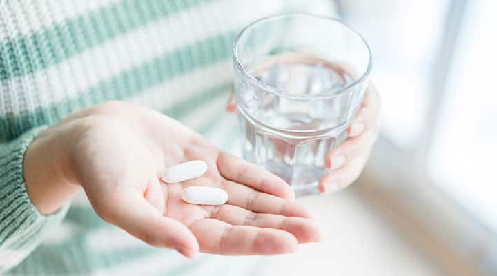 Woman holding two  cimetidine capsules for clinical trial on long-term cancer survival