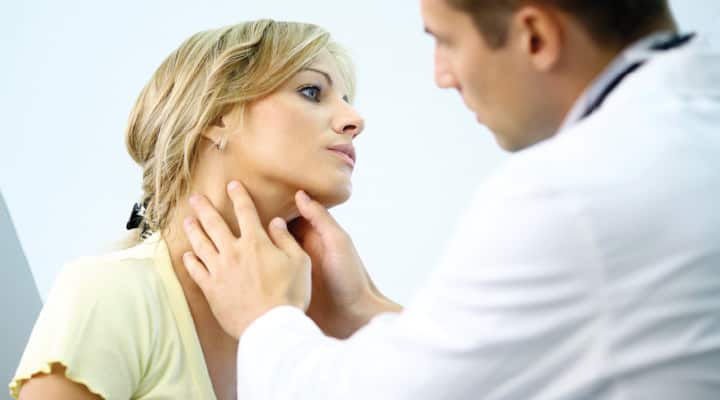 Doctor examining woman’s neck for symptoms of strep throat