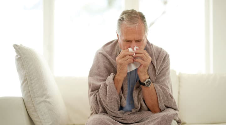 Man blowing nose from cold due to immune senescence