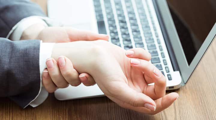 Business woman clutching their wrist in pain from carpal tunnel