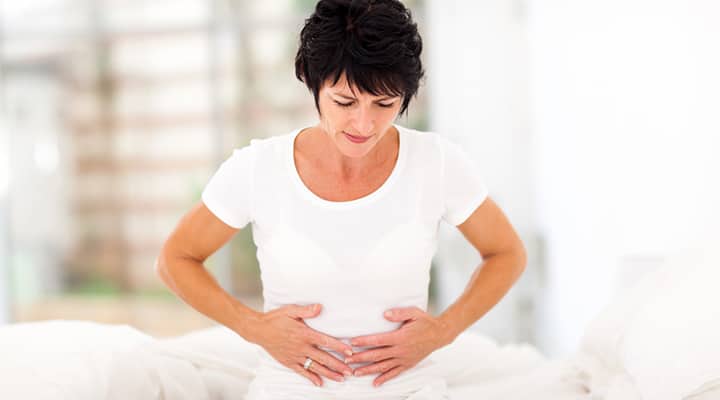 Frowning woman holding her abdomen in discomfort due to constipation