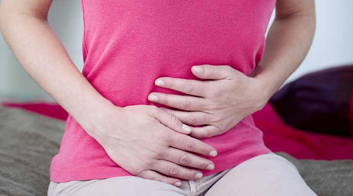 Woman pushing on her abdomen due to inflammatory bowel disease