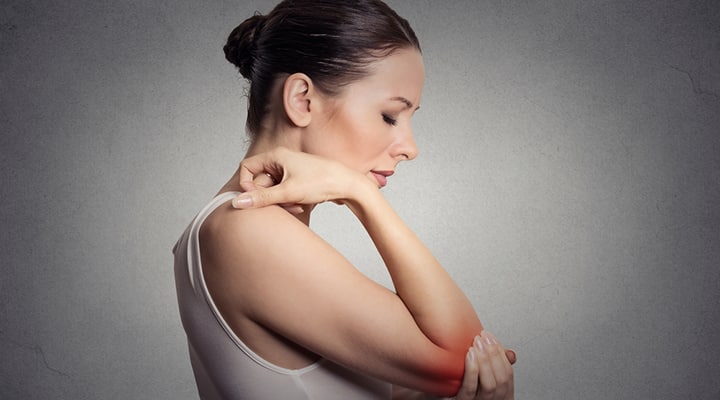 Woman clutching her elbow from chronic inflammation in the joint