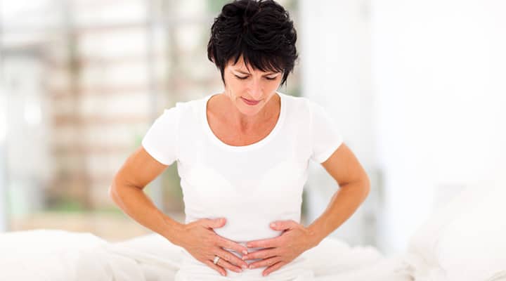 Frowning woman clutching abdomen from premenstrual syndrome symptoms