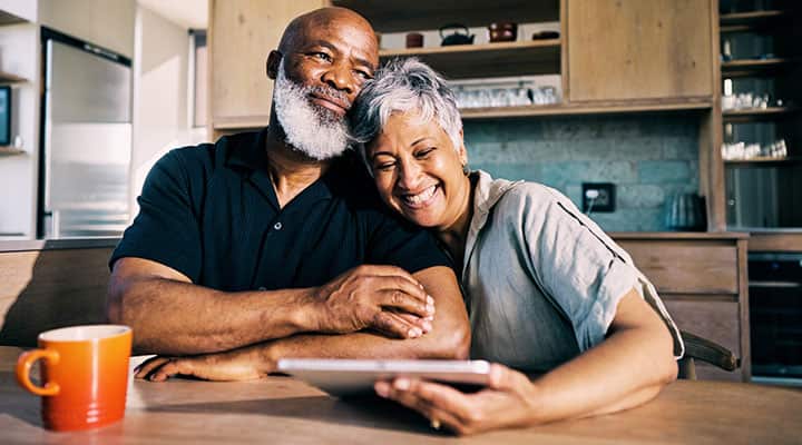 Husband and wife sitting at kitchen table smiling