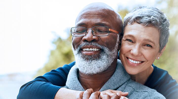 Loving wife embracing her aging husband from behind
