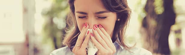 Woman blowing nose due to regional allergy