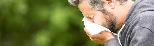 Man sneezing into tissue due to seasonal allergies