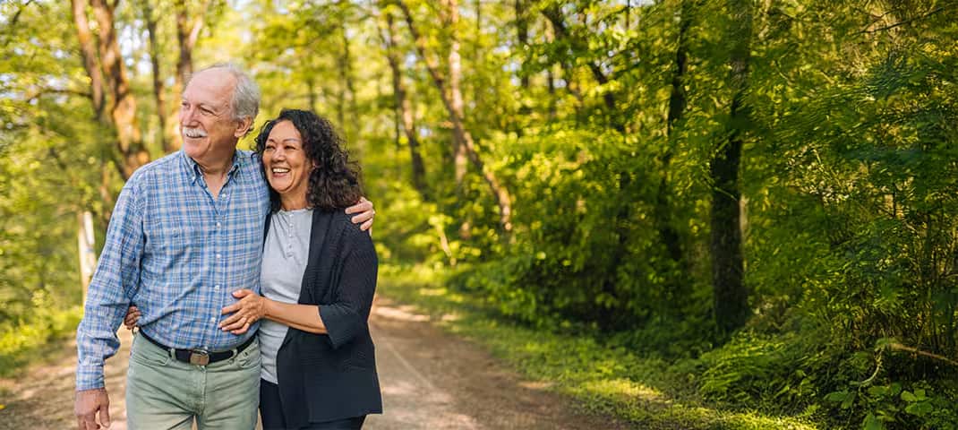 Senior couple holding each other while walking through a forest
