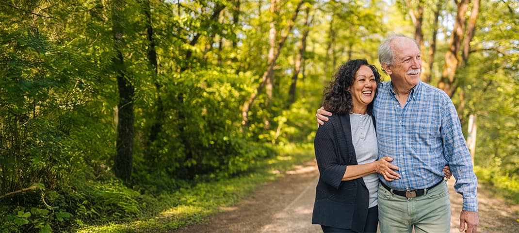 Senior couple holding each other while walking through a forest