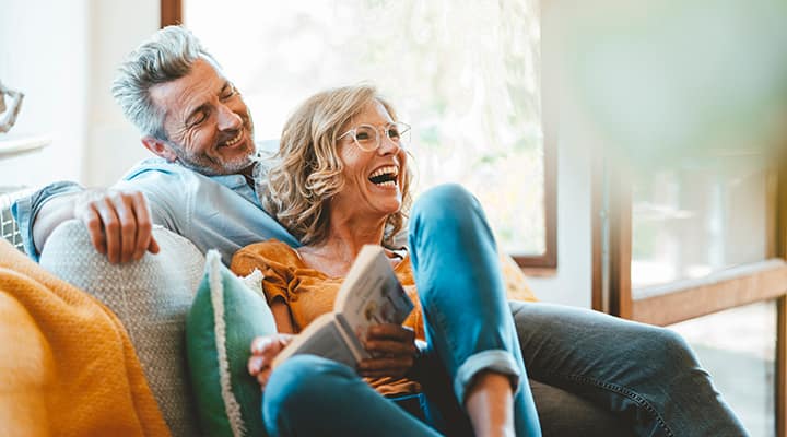 Mature couple laughing, sitting on a couch