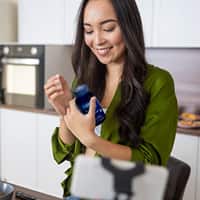 Woman reading the ingredients on a Life Extension's supplement bottle.