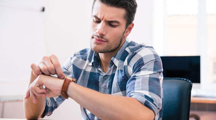 Man setting his wrist watch to better his concentration in alloted time