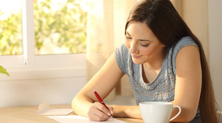 Woman writting her goals on paper in order to help achieve them
