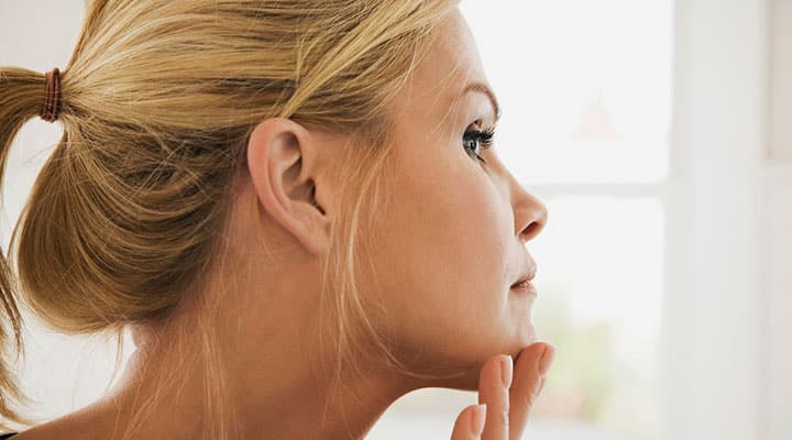Woman touching face while looking in the mirror
