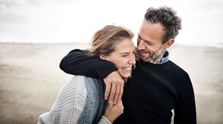 Couple on beach laughing away stress