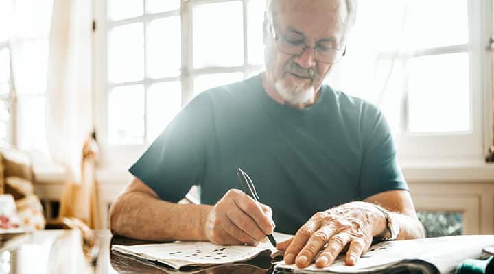 Older man doing crossword to keep his mind active to help reduce Alzheimer's risk