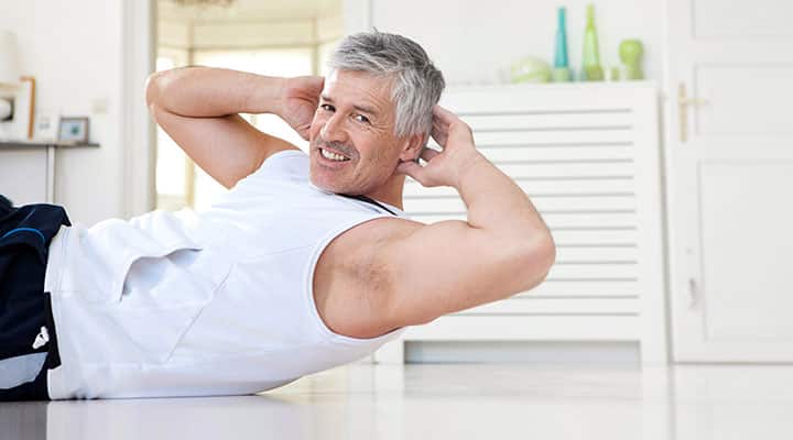 Older man in tank top doing crunch exercises