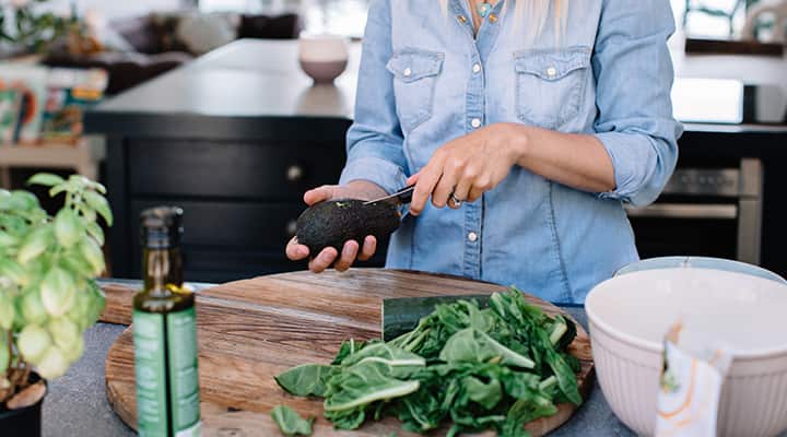 Woman cutting open avocado with tips for preparing keeping it from browning