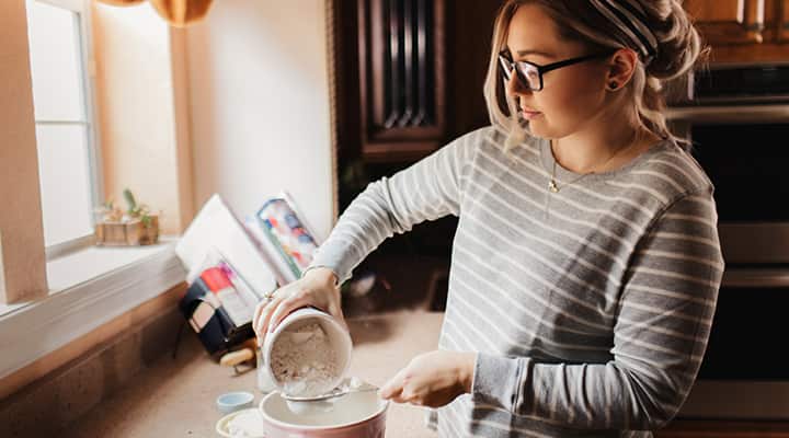 Woman pouring muscle and immune supporting protein powder through sieve
