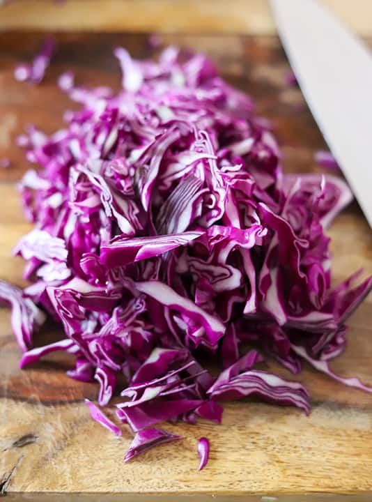 Chopped purple cabbage that will be added to a vegan Waldorf salad loaded with cruciferous vegetables