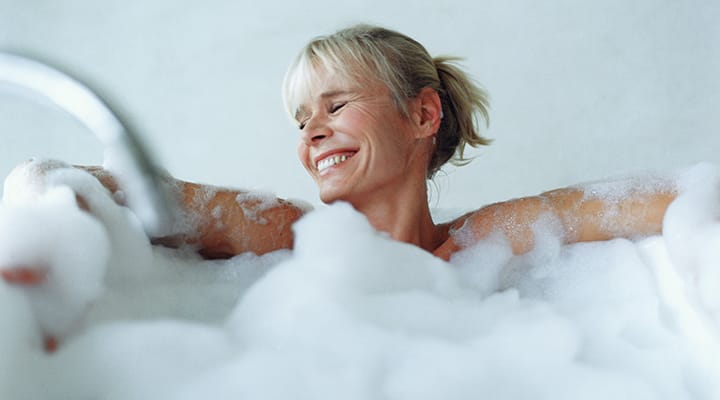 Smiling woman having a bubble bath that can be paired with stress relief supplements