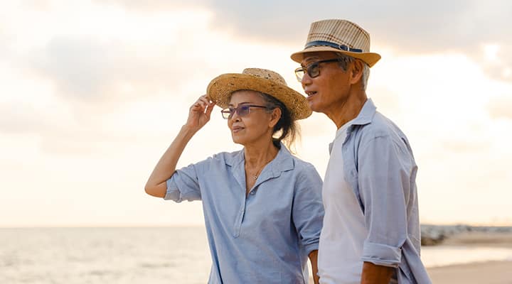 Older husband and wife walking along the beach
