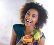 Woman smiling and holding citrus fruits