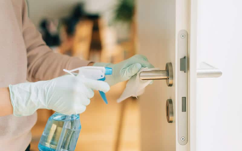 Hand with plastic glove cleaning door knob