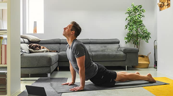 Man doing sun salutation yoga pose on mat